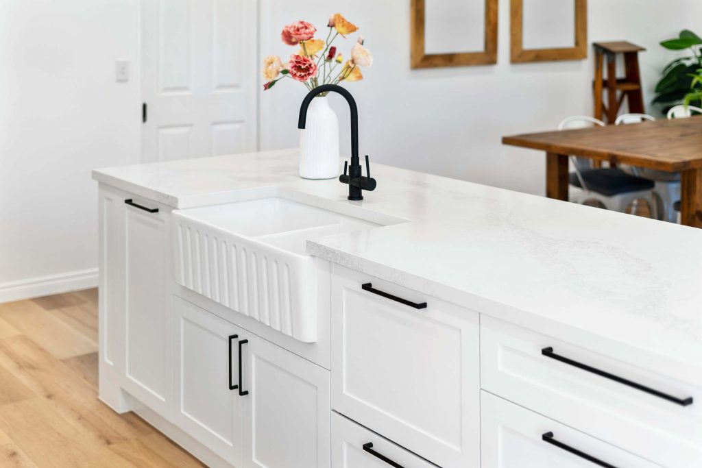 kitchen renovation with multi-purpose kitchen island with sink and tap, white marble and white cabinets